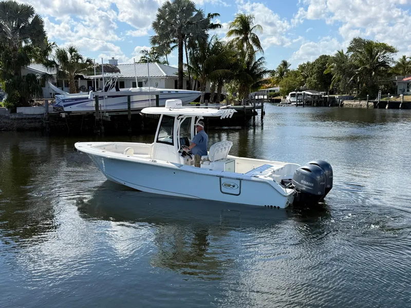 Slide: The Image of 2023 Sea Hunt Gamefish 25 boat cruising on a calm, scenic waterway with palm trees. - 2