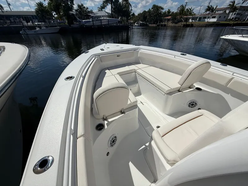 Slide: The Image of 2023 Sea Hunt Gamefish 25 boat interior with white seating, docked by a calm waterfront. - 27