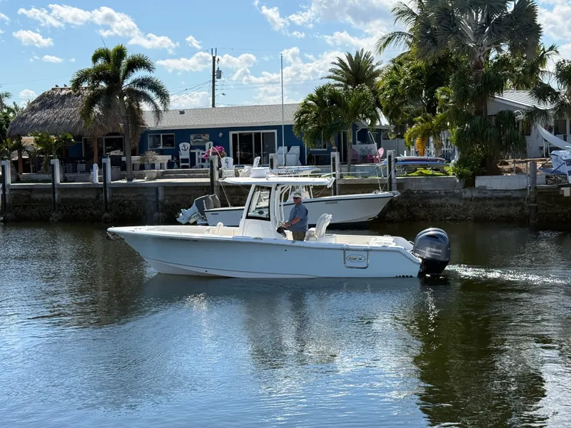 Slide: The Image of 2023 Sea Hunt Gamefish 25 boat cruising on a sunny day near a waterfront home. - 3