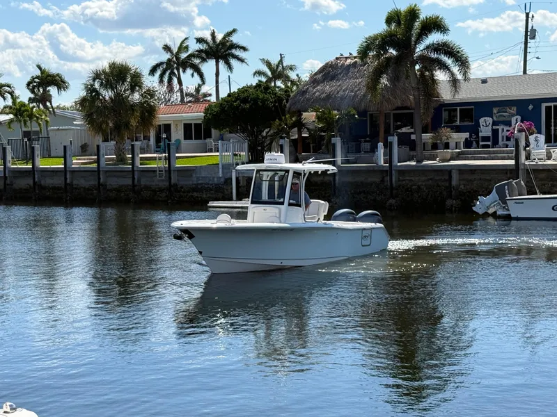 Slide: The Image of 2023 Sea Hunt Gamefish 25 boat cruising near a tropical waterfront with palm trees. - 4
