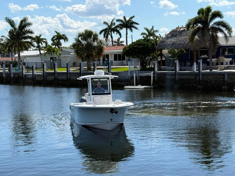 Slide: The Image of 2023 Sea Hunt Gamefish 25 boat cruising near waterfront homes and palm trees. - 5