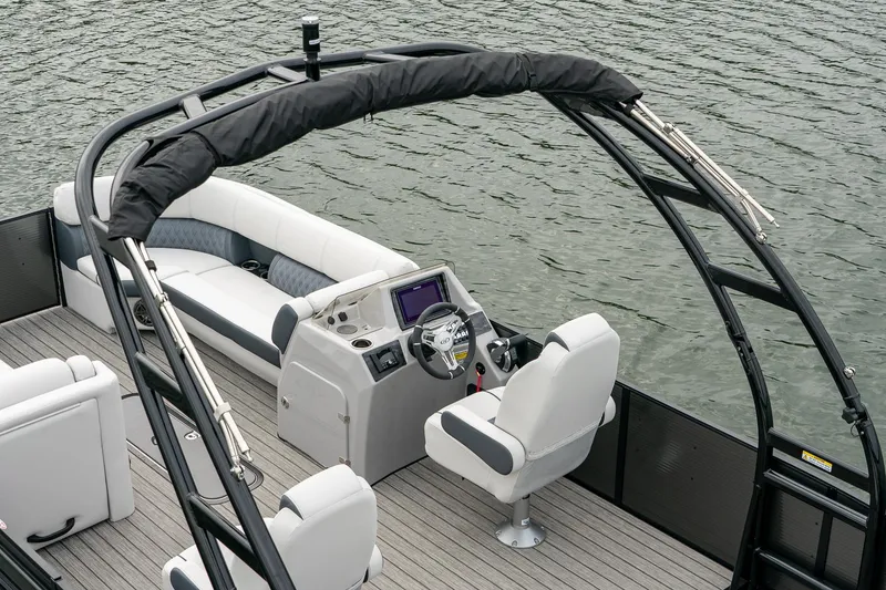 Slide: The Image of 2023 Harris 250 Sunliner Sport pontoon boat interior with helm and seating, on water. - 13
