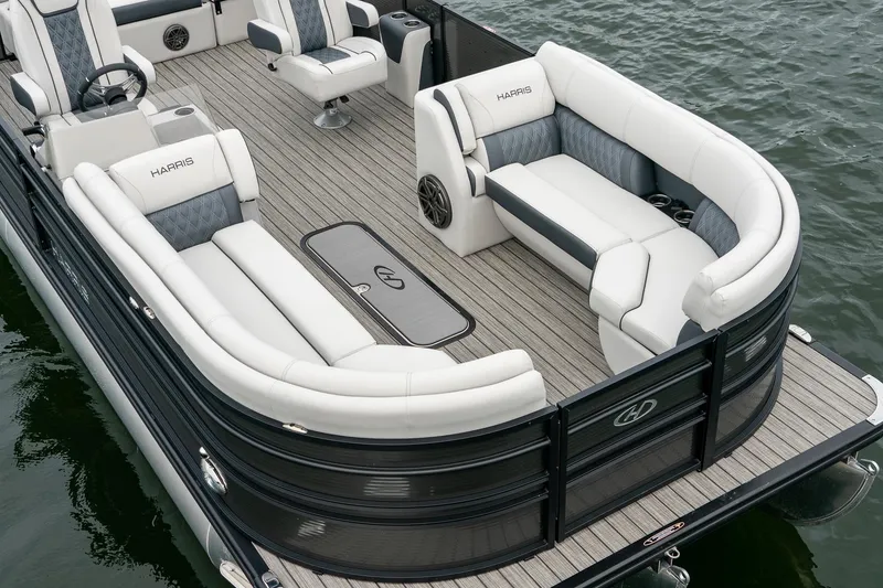 Slide: The Image of 2023 Harris 250 Sunliner Sport pontoon boat with luxurious seating on a calm lake. - 19