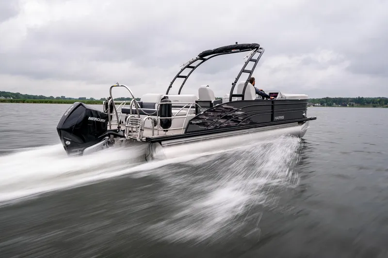 Slide: The Image of 2023 Harris 250 Sunliner Sport pontoon boat speeding on a lake under cloudy skies. - 3