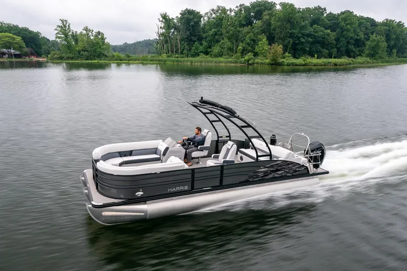 Slide: The Image of 2023 Harris 250 Sunliner Sport pontoon boat cruising on a serene lake. - 5