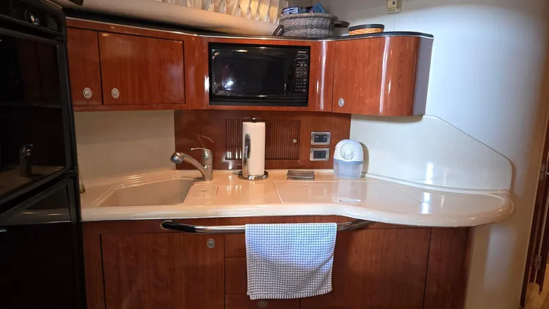 Slide: The Image of 2004 Sea Ray 380 Sundancer kitchen with wood cabinets, microwave, and sink. - 22