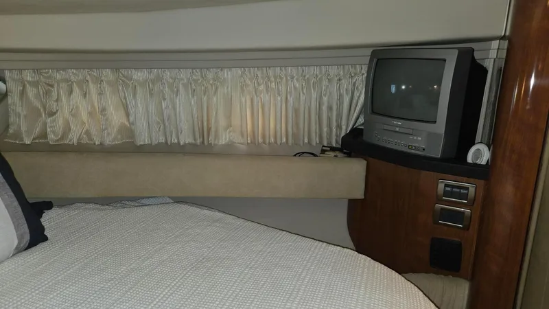 Slide: The Image of 2004 Sea Ray 380 Sundancer cabin with bed, TV, and curtains. - 26