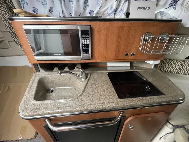 Slide: The Image of Compact kitchen in 2014 Stingray 250CS boat with sink, microwave, and stove. - 10