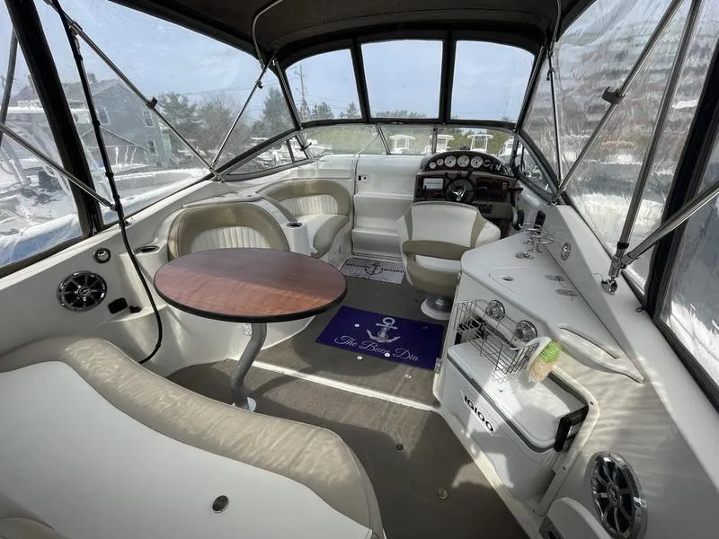 Slide: The Image of 2014 Stingray 250CS boat interior with seating, table, and helm, under a canopy. - 5