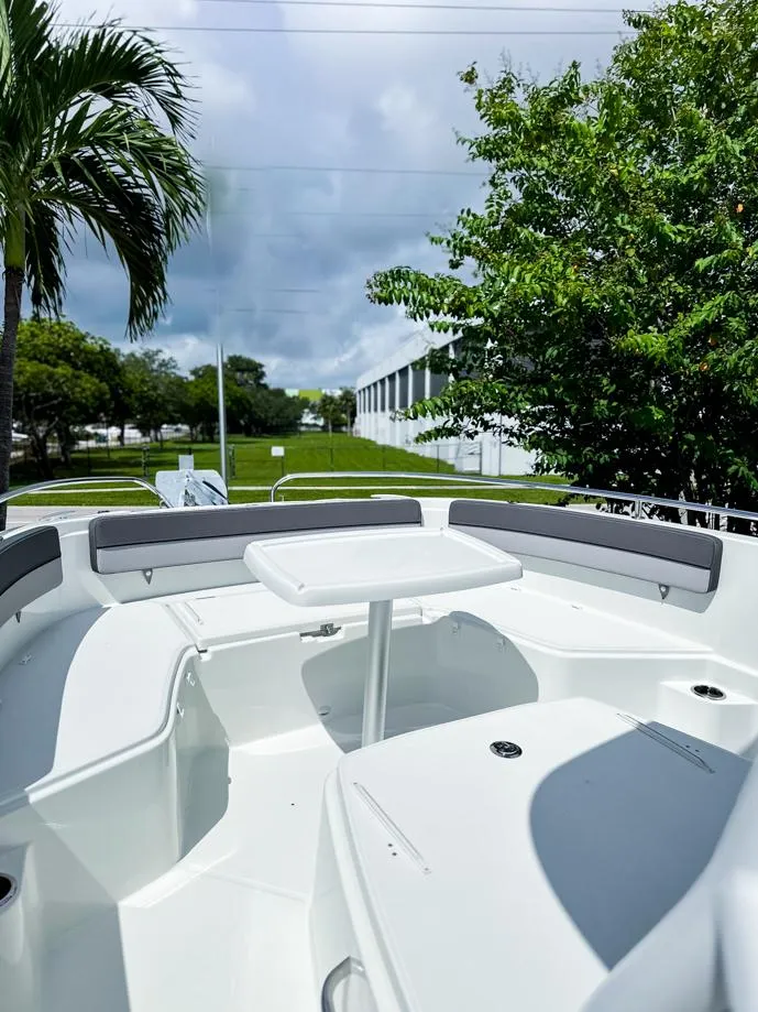 Slide: The Image of 2024 Jeanneau LEADER 9.0CC boat interior with seating and table, surrounded by lush greenery. - 17