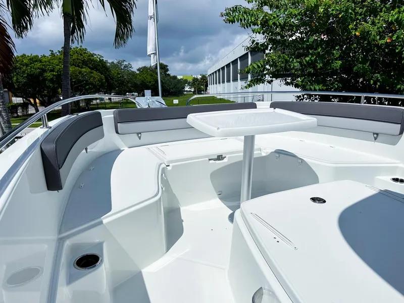 Slide: The Image of 2024 Jeanneau LEADER 9.0CC boat interior with seating and table, surrounded by lush greenery. - 18