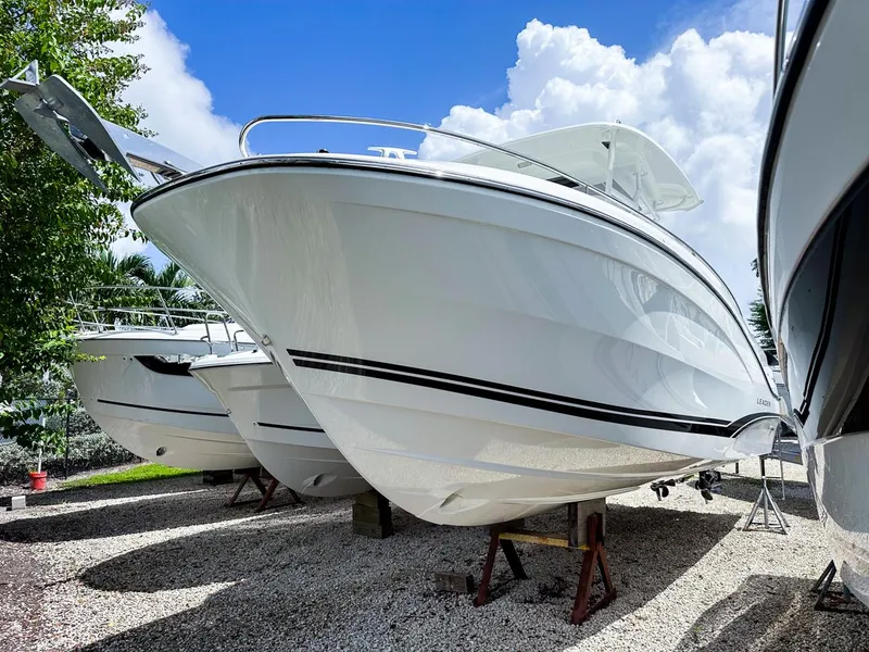 Slide: The Image of 2024 Jeanneau LEADER 9.0CC boat displayed outdoors on gravel, under a bright blue sky. - 3