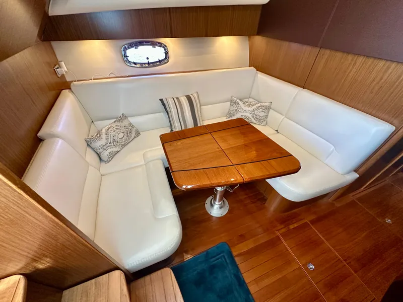 Slide: The Image of 2018 Tiara Yachts 4300 Open interior with white leather seating and wooden table. - 23