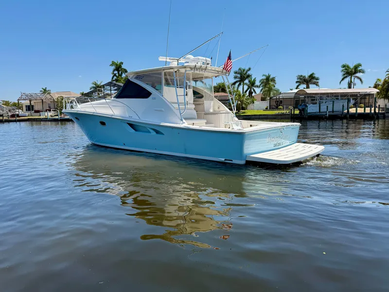 Slide: The Image of 2018 Tiara Yachts 4300 Open cruising on a sunny day, surrounded by palm trees. - 4