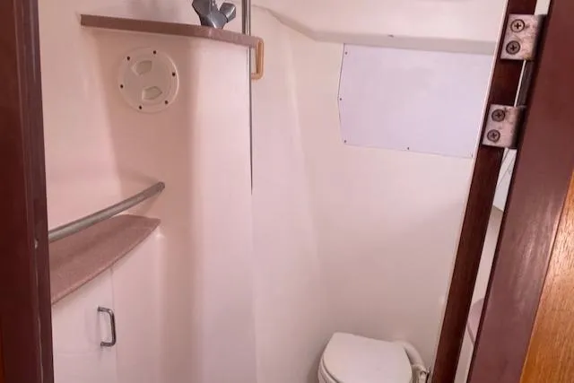 Slide: The Image of 1999 Hunter Passage 420 yacht bathroom with toilet, shelf, and storage cabinet. - 11