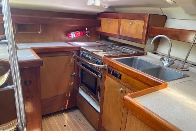 Slide: The Image of 1999 Hunter Passage 420 yacht kitchen with wood cabinetry, stove, and dual sink. - 4