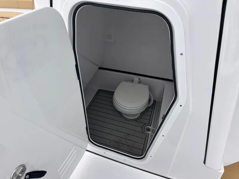 Slide: The Image of 2024 Sportsman Masters 267OE Bay Boat interior with open door revealing compact toilet. - 42