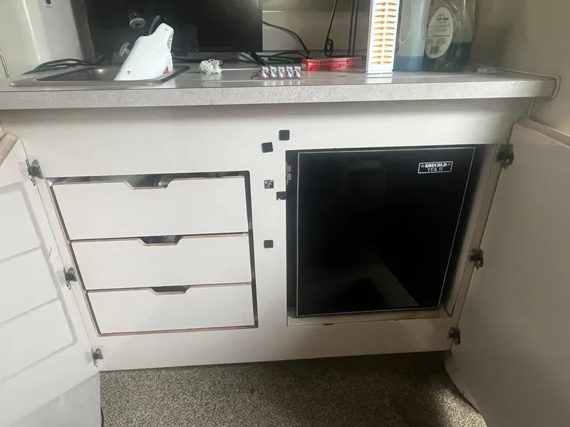 Slide: The Image of 1993 Regal 9.8 VENTURA boat interior with kitchenette, featuring drawers and a mini fridge. - 17