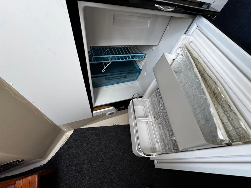 Slide: The Image of Open refrigerator inside 2005 Albin 26 Tournament Express boat, showing shelves and freezer compartment. - 11