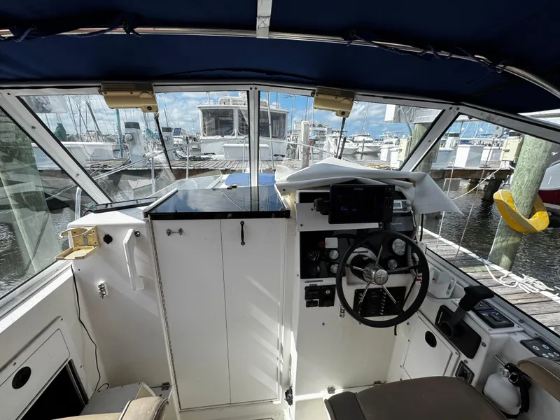 Slide: The Image of 2005 Albin 26 Tournament Express boat interior with steering wheel and marina view. - 2