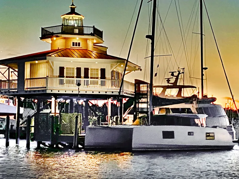 Slide: The Image of Nautitech 40 Open catamaran docked near a lighthouse at sunset, 2022 model. - 2