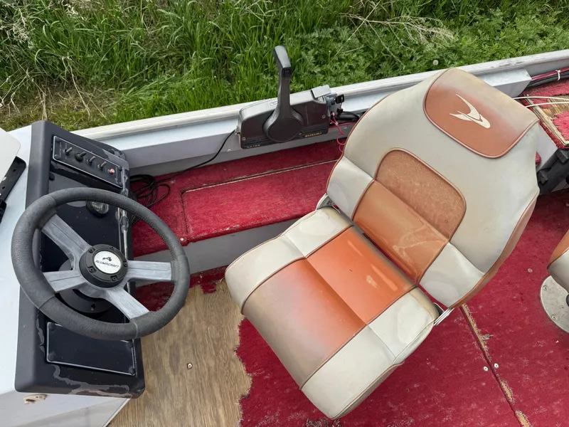 Slide: The Image of 1994 Alumacraft SC boat interior with steering wheel and seat, featuring red and beige upholstery. - 7