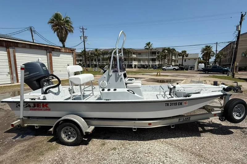Slide: The Image of 2014 Majek 18 Redfish boat on trailer, parked outdoors under clear sky. - 0