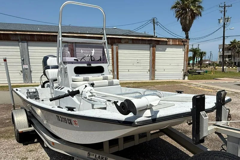Slide: The Image of 2014 Majek 18 Redfish boat on trailer, parked outdoors near garages. - 2