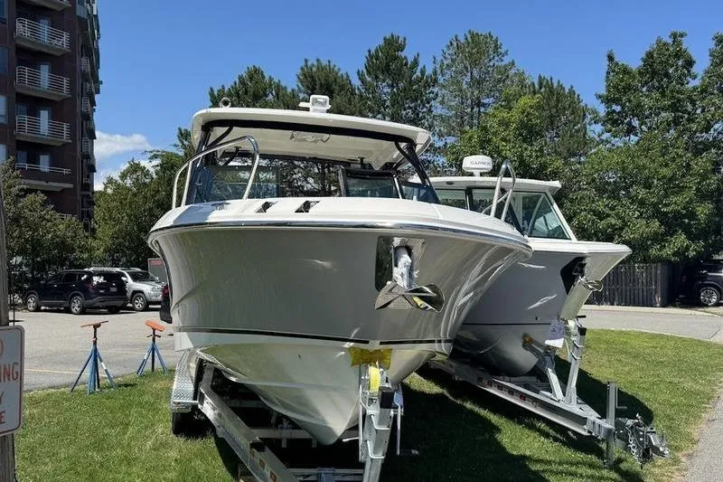 Slide: The Image of 2025 Boston Whaler 280 Vantage boats on trailers, parked outdoors. - 2