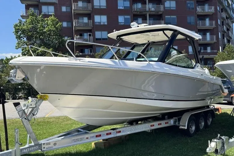 Slide: The Image of 2025 Boston Whaler 280 Vantage boat on trailer, parked near modern building. - 5