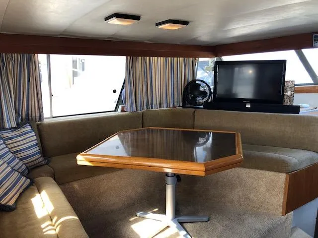 Slide: The Image of 1988 Bayliner 3818 Motoryacht interior with cozy seating, striped curtains, and a wooden table. - 12