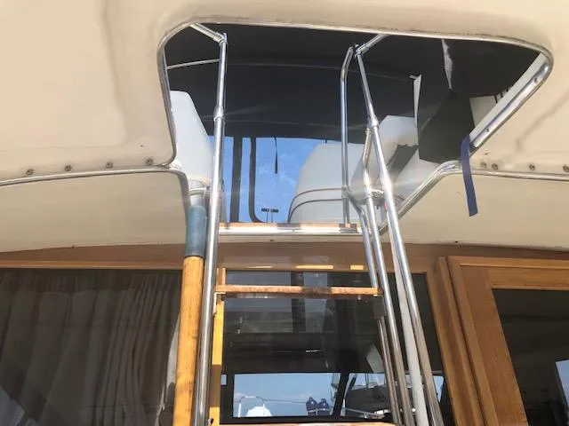 Slide: The Image of 1988 Bayliner 3818 Motoryacht with wooden ladder and metal railings, leading to upper deck. - 2