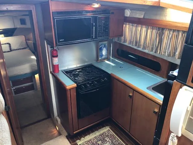 Slide: The Image of 1988 Bayliner 3818 Motoryacht interior kitchen with stove, microwave, and wooden cabinetry. - 27