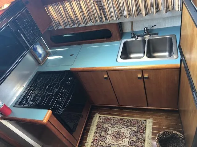 Slide: The Image of 1988 Bayliner 3818 Motoryacht kitchen with stove, double sink, and wooden cabinets. - 28
