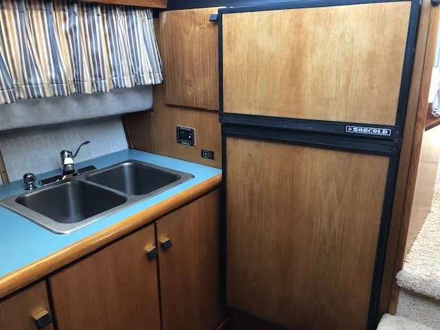Slide: The Image of 1988 Bayliner 3818 Motoryacht kitchen with dual sink, wooden cabinets, and refrigerator. - 32