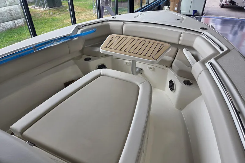 Slide: The Image of 2026 Boston Whaler 280 Outrage interior with cushioned seating and wooden table. - 13