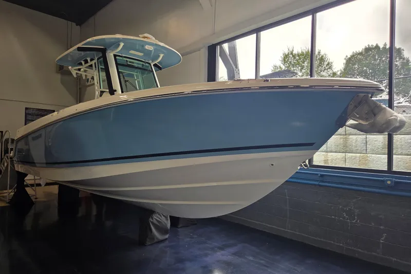 The Image of 2026 Boston Whaler 280 Outrage boat in showroom, featuring sleek blue hull design. - 2