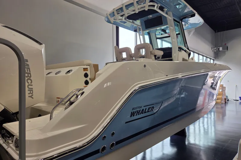 Slide: The Image of 2026 Boston Whaler 280 Outrage boat in showroom, featuring sleek design and Mercury engine. - 4