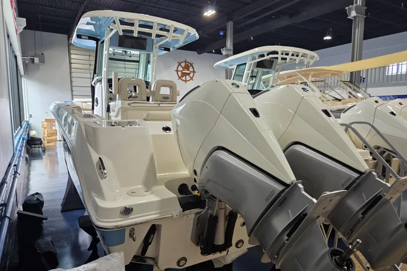Slide: The Image of 2026 Boston Whaler 280 Outrage boat with dual engines in showroom setting. - 5
