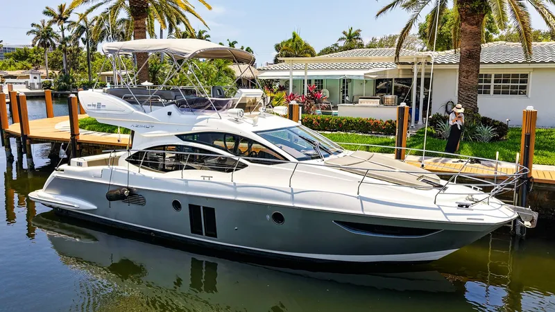 The Image of Azimut 42 Fly 2017 yacht docked by a waterfront home with palm trees. - 1