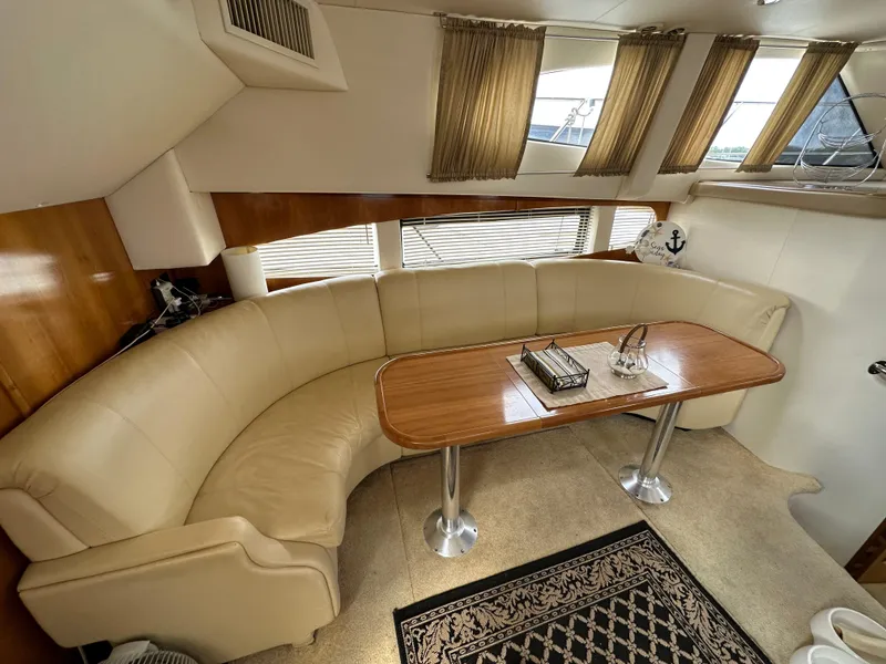 Slide: The Image of Luxurious 2002 Carver AFT CABIN interior with curved seating and elegant wooden table. - 12