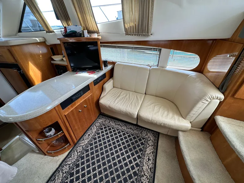 Slide: The Image of 2002 Carver AFT CABIN interior with cream sofa, TV, and wooden cabinetry. - 13