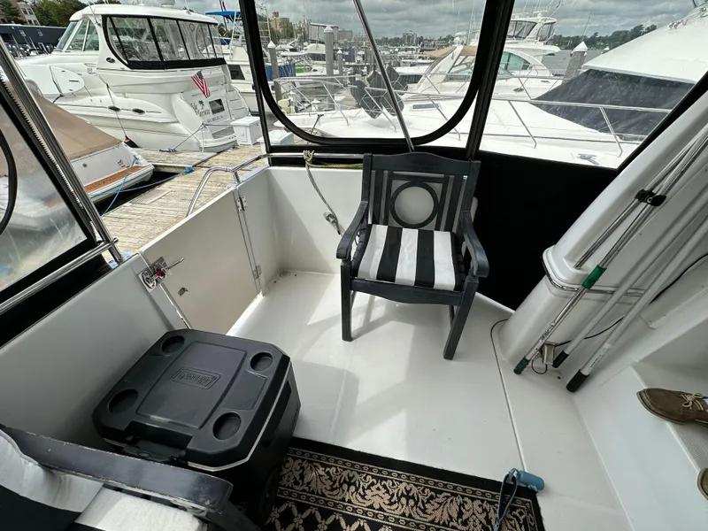 Slide: The Image of 2002 Carver AFT CABIN boat interior with chair, cooler, and marina view. - 21
