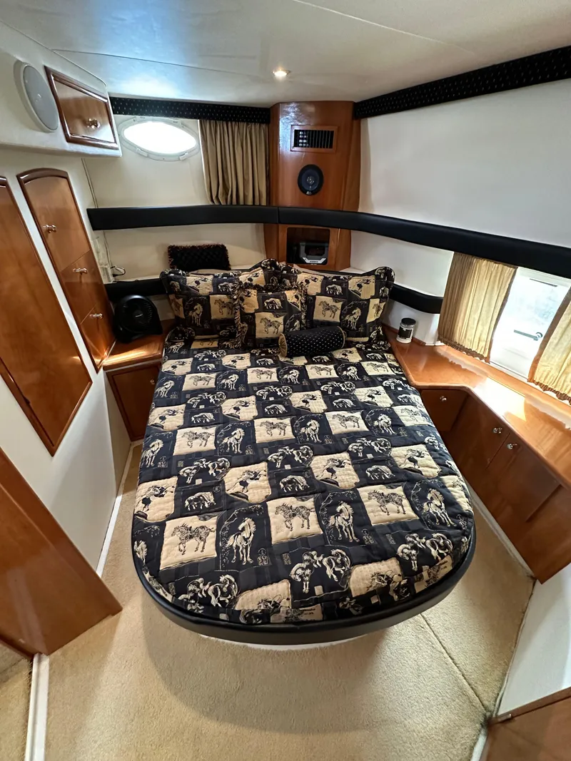 Slide: The Image of 2002 Carver AFT CABIN bedroom with patterned bedding and wooden cabinetry. - 8