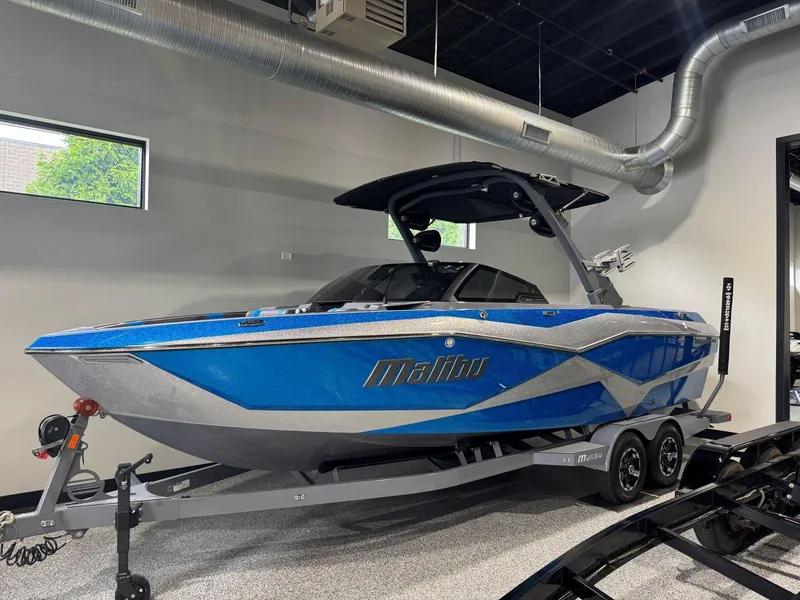 The Image of 2022 Malibu Wakesetter 25 LSV boat in showroom, blue and silver design. - 0