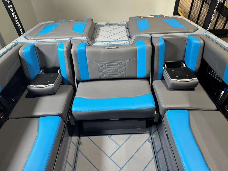 Slide: The Image of 2022 Malibu Wakesetter 25 LSV interior with gray and blue seating, cup holders, and storage compartments. - 24