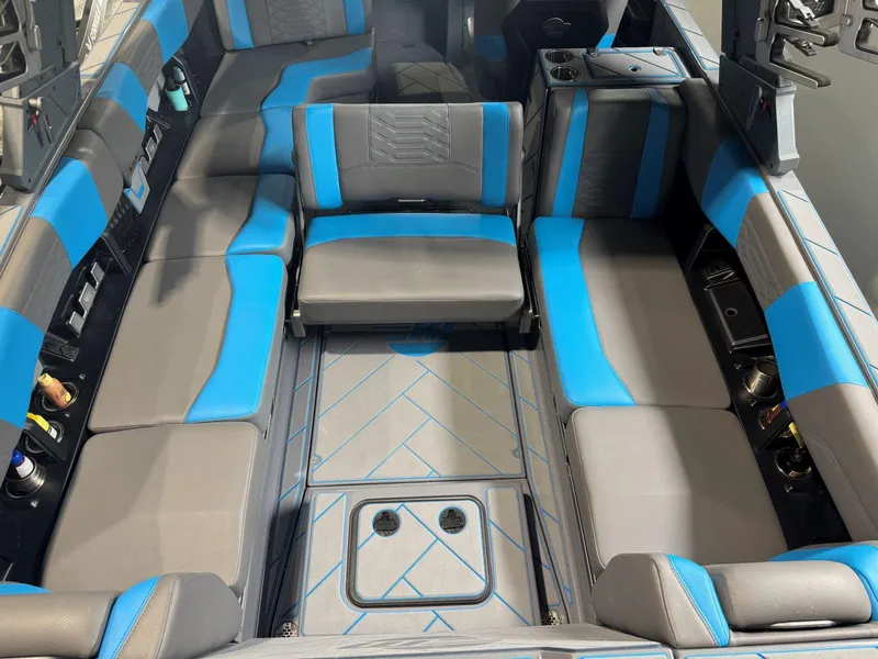 Slide: The Image of 2022 Malibu Wakesetter 25 LSV interior with blue and gray seating, cup holders, and storage compartments. - 29
