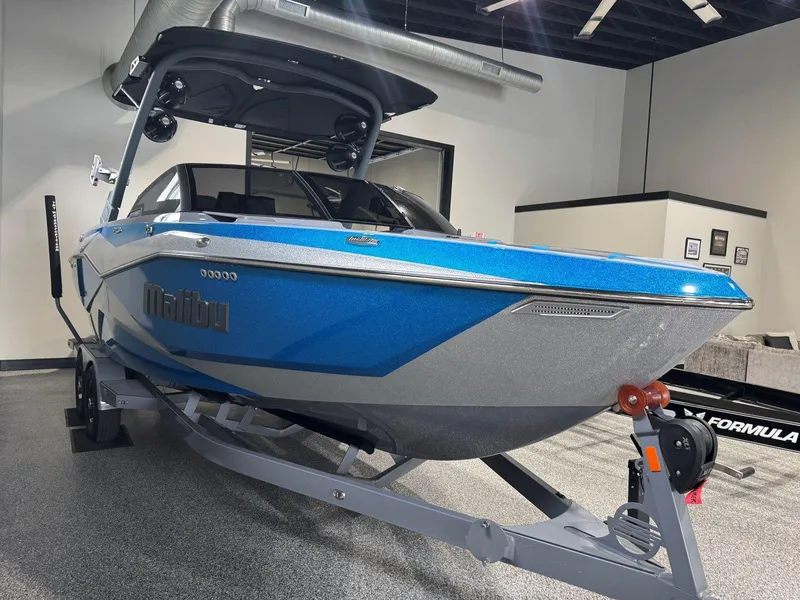 Slide: The Image of 2022 Malibu Wakesetter 25 LSV boat in showroom, blue and silver design on trailer. - 4