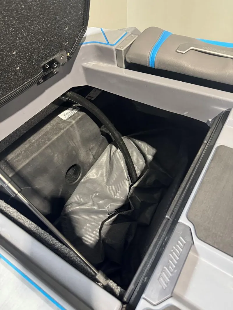 Slide: The Image of 2022 Malibu Wakesetter 25 LSV storage compartment with black interior and blue accents. - 44