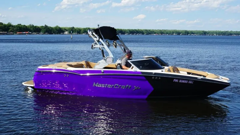 Slide: The Image of 2019 MasterCraft XStar boat on a lake with a vibrant purple hull. - 4